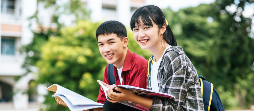 Male female students sitting reading books